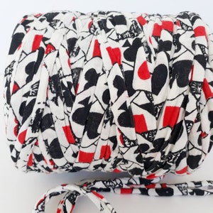 May include: A roll of white, red, and black t-shirt yarn with a playing card pattern. The yarn is made from recycled t-shirts.