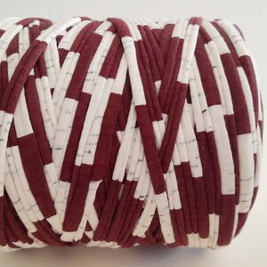 May include: A roll of red and white striped yarn. The yarn is made of fabric scraps and is perfect for crocheting or knitting.