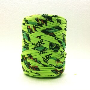 May include: A spool of bright green yarn with a checkered and racing car print.