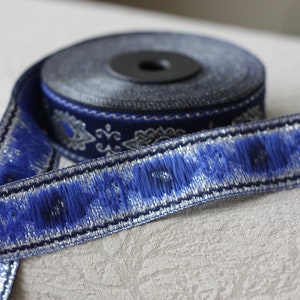 Puede incluir: Borde azul y plateado con un patr&oacute;n decorativo. El borde est&aacute; enrollado en un carrete.