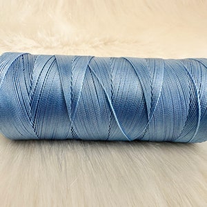 May include: A spool of light blue thread.