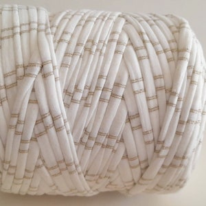 May include: A white and gold striped yarn ball. The yarn is made of a soft, textured fabric and is perfect for crocheting or knitting.