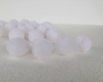 Può includere: Una collezione di piccoli pompon bianchi e soffici sparsi su una superficie strutturata. I pompon sono rotondi e hanno una consistenza morbida e sfocata. Lo sfondo è di un colore chiaro e uniforme, che fornisce uno sfondo neutro.