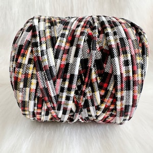 May include: A roll of black, white, red, and yellow plaid yarn.