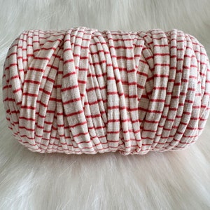May include: A roll of red and white striped yarn. The yarn is made of a soft, textured material and is perfect for crocheting or knitting.