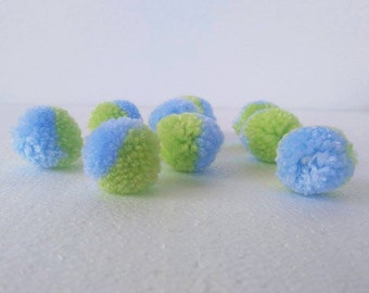 Può includere: Una collezione di soffici pompon nei toni del blu e del verde. Ogni pompon è diviso in due colori, creando un aspetto giocoso e vibrante. Queste decorazioni rotonde e morbide sono ideali per progetti di artigianato.