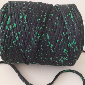 May include: A roll of black and green yarn with a speckled pattern. The yarn is made of recycled t-shirts.