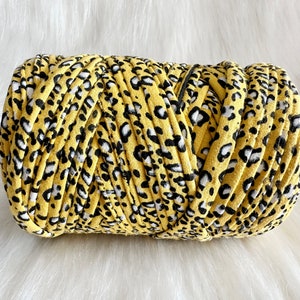 May include: A roll of yellow, black, and white patterned yarn. The yarn has a leopard print design.