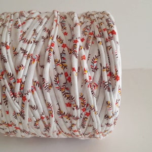 May include: A roll of white cotton rope with a floral print in shades of red, orange, and brown.