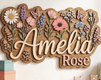 以下が含まれることがあります： 木製のサインで、筆記体の「Amelia Rose」という名前が、レーザーカットされた花と蝶で飾られています。サインは自然な仕上がりの木材でできており、花はピンク、紫、青など様々な色で塗装されています。装飾的なアイテムです。