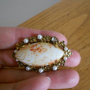 Vintage spotted milk stone or cabochon in a goldtone setting.  Orange and gold oval brooch.