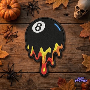 May include: A circular embroidered patch featuring a black billiard ball with the number eight in white, accented by a blue highlight. The bottom portion of the patch displays a dripping effect in vibrant shades of yellow, orange, and red.