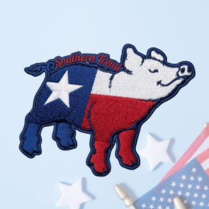 May include: An embroidered patch shaped like a pig with the Texas state flag design, featuring a blue section with a white star, a white middle, and a red lower section. The text Southern Trend is stitched in red above the pig's back.