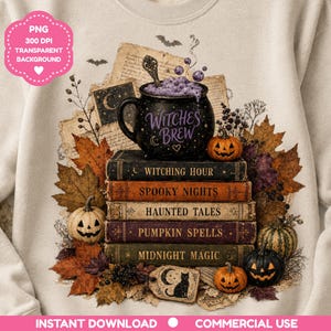 Op de afbeelding: Een beige sweatshirt met een afbeelding van een zwarte ketel met het opschrift Witches Brew, rustend op een stapel van vijf vintage boeken getiteld Witching Hour, Spooky Nights, Haunted Tales, Pumpkin Spells en Midnight Magic, omringd door herfstbladeren.