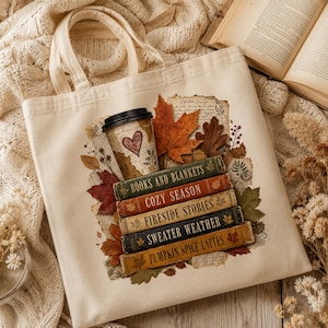 Natural canvas tote bag with autumn book stack design featuring books and blankets, cozy season, fireside stories, coffee and colorful fall leaves.