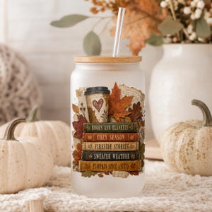 Frosted glass can tumbler with autumn book lover design featuring stacked books, pumpkin spice lattes, coffee cup, maple leaves and cozy fall artwork.
