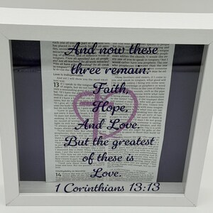 Puede incluir: Obra de arte enmarcada en blanco con texto de 1 Corintios 13:13. El texto dice: «Y ahora permanecen la fe, la esperanza y el amor, estos tres; pero el mayor de ellos es el amor».