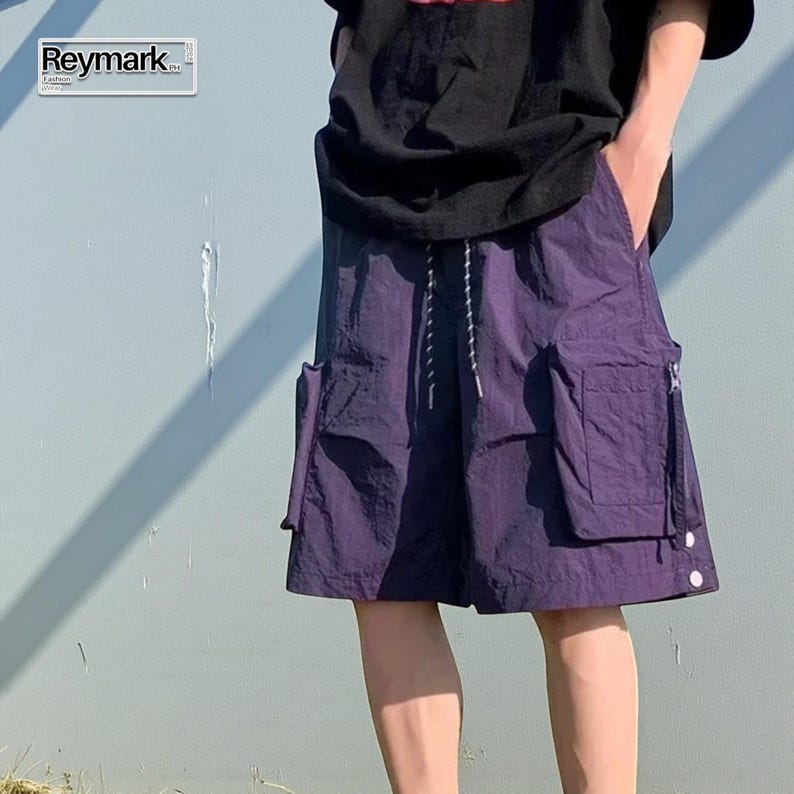 Multi Pocket Cargo Shorts | Men Baggy Streetwear Shorts | Casual Summer Outfit | Oversized Hip Hop Shorts | Gift for Him
.
Person wearing loose-fit black cargo shorts with multiple flap and zipper pockets, standing outdoors on a grassy field under a clear sky.