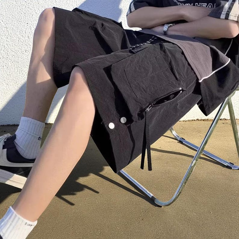 Multi Pocket Cargo Shorts | Men Baggy Streetwear Shorts | Casual Summer Outfit | Oversized Hip Hop Shorts | Gift for Him
.
Person wearing loose-fit black cargo shorts with multiple flap and zipper pockets, standing outdoors on a grassy field under a clear sky.