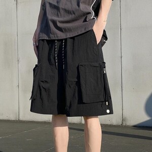 Multi Pocket Cargo Shorts | Men Baggy Streetwear Shorts | Casual Summer Outfit | Oversized Hip Hop Shorts | Gift for Him
.
Person wearing loose-fit black cargo shorts with multiple flap and zipper pockets, standing outdoors on a grassy field under a clear sky.