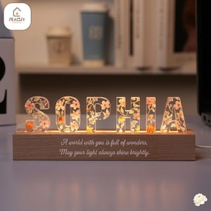 Puede incluir: Una taza de cerámica blanca con un asa negra y el texto "But First, Coffee" en negro, con una fuente de estilo manuscrito. La taza está sobre una superficie blanca.