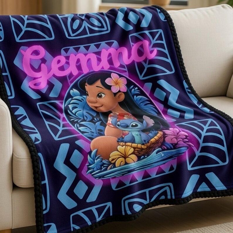 Puede incluir: Una manta azul marino con una ilustraci&oacute;n de dibujos animados de Lilo y Stitch. La manta tiene un patr&oacute;n geom&eacute;trico repetitivo en azul y morado, con el nombre "Gemma" en rosa. Los bordes est&aacute;n adornados con un borde negro con pompones.