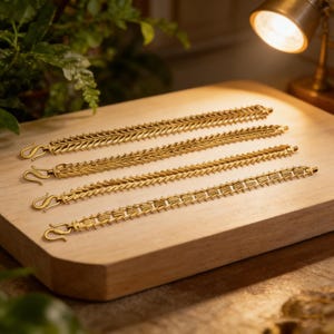 May include: Four gold-colored bracelets with intricate, textured designs are displayed on a wooden surface. Each bracelet features a unique pattern and a hook clasp. The bracelets are arranged horizontally, showcasing their details.