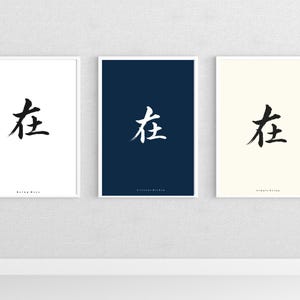 May include: Three framed art prints with a minimalist design. Each print features a black calligraphic character on a white, navy blue, and cream background. The prints are displayed on a white wall.