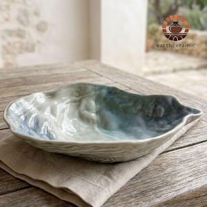 Pode incluir: Um conjunto de três canecas de cerâmica com esmalte creme salpicado. Cada caneca apresenta um design pintado à mão diferente: uma folha azul e verde, uma flor amarela e uma baga vermelha. As canecas têm um design simples e moderno.