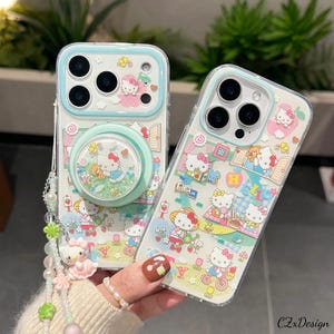 Pu&ograve; includere: Due custodie trasparenti per telefono a tema Hello Kitty. Una custodia ha un pop socket con glitter e un design Hello Kitty. Entrambe le custodie presentano un bordo azzurro e sono decorate con personaggi di Hello Kitty in varie scene.