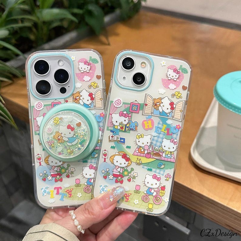 Pu&ograve; includere: Custodie trasparenti per telefono con un design di Hello Kitty. Le custodie hanno un bordo azzurro e un supporto per telefono con glitter. Il design include personaggi di Hello Kitty, fiori e altri elementi decorativi. Le custodie sono per un telefono.