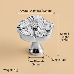 May include: A silver-coloured flower-shaped cabinet knob with a reflective finish. The knob has an overall diameter of 33mm, an overall height of 30mm, a base diameter of 14mm, a single hole for mounting, and a total weight of 70g as labelled.
