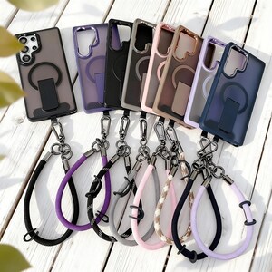 May include: A collection of phone cases in various colors, each with a matching wrist strap. The cases are clear with colored borders and a magnetic ring. Wrist straps come in black, purple, gray, pink, and patterned designs.