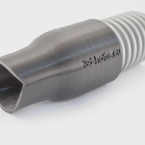 Könnte beinhalten: Ein zylindrischer Adapter in Schwarz und Hellgrau mit einer herzförmigen Öffnung an einem Ende und einem gerippten Gewindeanschluss am anderen. Der schwarze Teil zeigt den geprägten Text 3d-hütte.eu an der Seite und hat eine feste Struktur.