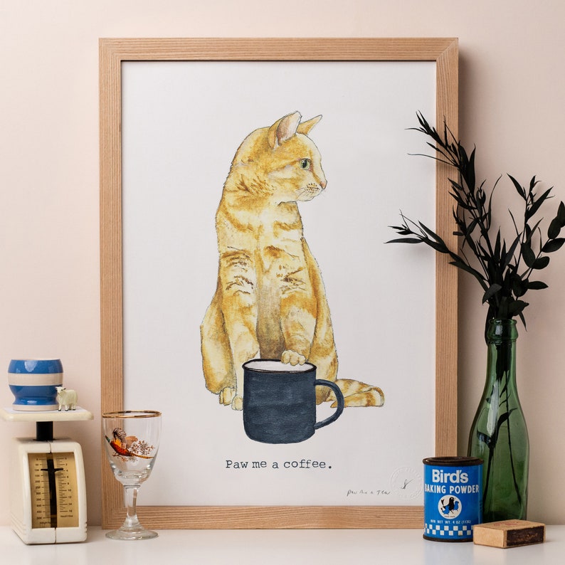 May include: A watercolor illustration of an orange tabby cat holding a black coffee mug. The cat is looking to the right and the text "Paw me a coffee." is below the cat.