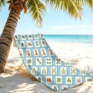 May include: A beach chair featuring a light blue fabric cover printed with a repeating pattern of white mahjong tiles. Each tile displays distinct black, red, and green Chinese characters and symbols, including numbers and floral designs, arranged in a grid.