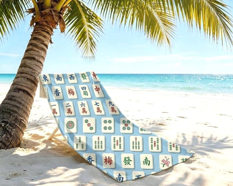 May include: A beach chair featuring a light blue fabric cover printed with a repeating pattern of various Mahjong tiles. The tiles display traditional Chinese characters, numbers, and circular symbols in red, green, and black ink colours.