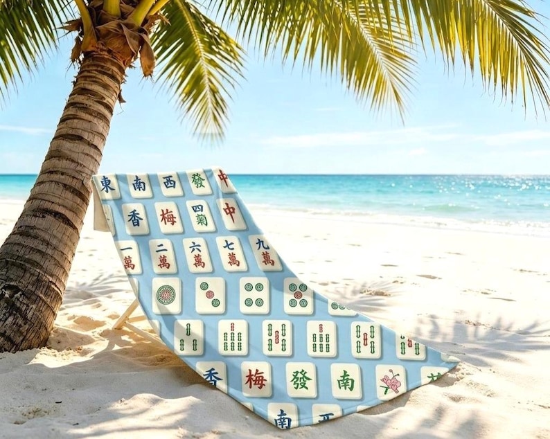 May include: A beach chair featuring a light blue fabric cover printed with a repeating pattern of white mahjong tiles. Each tile displays distinct black, red, and green Chinese characters and symbols, including numbers and floral designs, arranged in a grid.