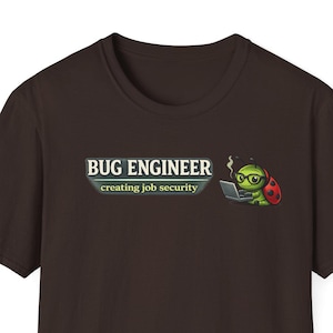 Può includere: T-shirt marrone scuro con la scritta "BUG ENGINEER" e "creating job security". Una coccinella dei cartoni animati con gli occhiali e un computer portatile si trova a destra del testo.
