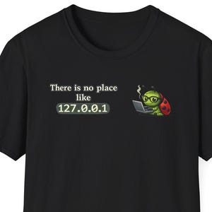 May include: Black t-shirt with the text "There is no place like 127.0.0.1" and a cartoon ladybug wearing glasses and working on a laptop. The ladybug is red with black spots and the laptop is grey.