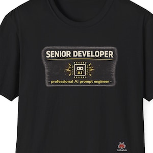 May include: Black t-shirt with a rectangular graphic that reads "SENIOR DEVELOPER" in gold lettering. Below the text is an AI graphic and the words "professional AI prompt engineer". The shirt has short sleeves and a crew neck.