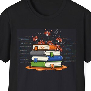 Op de afbeelding: Zwart t-shirt met een afbeelding van een stapel boeken met oranje, blauwe en groene kaften. De boeken hebben bladwijzers en zijn omringd door lieveheersbeestjes. De achtergrond heeft een computercode-ontwerp.