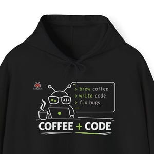 Può includere: Una tazza di ceramica bianca con manico nero e la scritta "But First, Coffee" in grassetto nero. La tazza è appoggiata su una superficie di legno. La tazza è alta 10 cm.