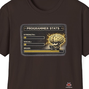 May include: A brown t-shirt with a graphic displaying "PROGRAMMER STATS." The graphic shows a brain illustration with bars for strength, social, and brain power. The shirt has a crew neck and short sleeves.