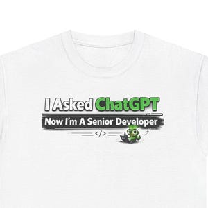May include: White t-shirt with the text "I Asked ChatGPT Now I'm a Senior Developer" in black and green. A small green frog graphic is below the text. The shirt is a casual, everyday wear item.