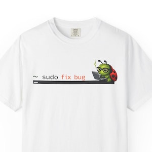 Może przedstawiać: Biała koszulka z grafiką przedstawiającą kreskówkową biedronkę w okularach, pracującą na laptopie. Tekst "sudo fix bug" jest wydrukowany nad biedronką. Koszulka ma okrągły dekolt.
