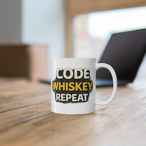 May include: White ceramic mug with the words "CODE WHISKEY REPEAT" in a distressed font. The mug is on a wooden surface, with a laptop in the background. The mug has a curved handle.
