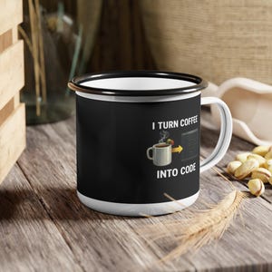 Puede incluir: Una taza de café de esmalte blanco con borde y asa negros. La taza presenta el texto "I TURN COFFEE INTO CODE" con una ilustración de una taza de café y código. La taza está sobre una superficie de madera.