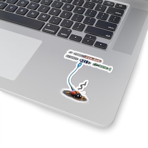 Może przedstawiać: Naklejka przedstawiająca biedronkę podłączoną do niebiesko-białego kabla Ethernet, z tekstem "TODO: FIX-BUG prompt AI: // done." Naklejka znajduje się na laptopie, z klawiaturą w tle.