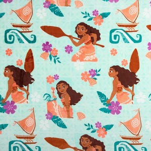 May include: A light blue fabric featuring a repeating pattern of a Polynesian woman, boats, flowers, and other tropical elements. The woman is depicted in a traditional outfit, holding a paddle. The design includes coral, orange, and purple accents.